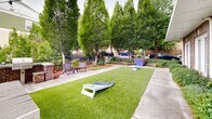 Located at 306 Ardmore Cir NW in Atlanta's vibrant Midtown area, this outdoor courtyard amenity space offers a well-appointed and inviting environment designed for community gathering and recreation. The centerpiece of the space is a generously sized artificial turf lawn, providing a clean, low-maintenance green surface perfect for lawn games such as cornhole, which is set up and ready for play.

Surrounding the turf, wide concrete pathways lead to a dedicated outdoor lounge area furnished with a sectional sofa, dining table, and chairs — ideal for casual gatherings or al fresco dining. A built-in brick grill station anchors one end of the patio, offering a functional outdoor cooking area for residents and guests. Lounge chairs nearby provide additional seating for relaxation.

Mature columnar trees and lush landscaping with colorful plantings frame the perimeter of the space, offering both privacy and a natural, park-like ambiance. Wrought-iron fencing delineates the boundary while maintaining open sightlines to the surrounding neighborhood. Overhead string lights add warmth and charm to the setting, making it equally inviting during evening hours.

The courtyard is set against the backdrop of the multi-story Ardmore building, whose brick and green exterior façade lends a modern yet classic character to the overall aesthetic. This thoughtfully designed outdoor space balances functionality, comfort, and greenery in an urban setting.
