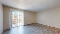 This single-story unit offers a practical and well-organized layout across two bedrooms and two bathrooms. The open living area is finished with durable wood-style laminate flooring and features a textured ceiling throughout. A sliding glass door fitted with vertical blinds fills the living space with natural light and provides direct access to an outdoor area. A ceiling fan is positioned overhead, serving both the living and adjacent dining areas.

The kitchen is efficiently designed with white cabinetry, a white tile backsplash, light countertops, and an under-cabinet range hood. Black appliances, including an electric range, dishwasher, and a stainless steel refrigerator, are included. Light wood-style flooring extends through the kitchen, which opens directly to the main living area.

The primary bedroom is generously sized, featuring carpeted flooring, a window for natural light, and access to a walk-in closet with rod and shelf storage. The second bedroom is similarly carpeted. A dedicated laundry alcove with washer/dryer hookups, built-in shelving, and a dryer vent connection adds notable convenience. Both bathrooms feature wood-style flooring, vanities with light countertops, and mirrors.
