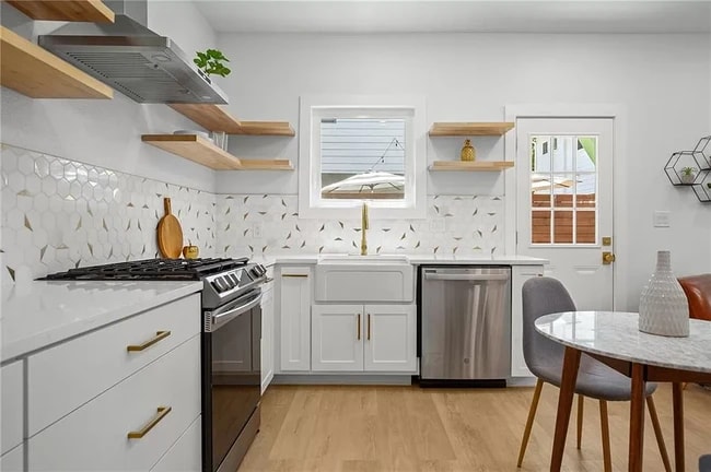 Open shelving system, light wood shelves, white cabinetry and countertops, & ample storage space. - 5402 Duval St