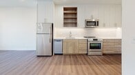 Located at 3009 W Leigh St in Richmond, Virginia, this single-floor unit offers a thoughtfully designed contemporary interior with a cohesive palette of neutral tones and modern materials throughout.

The kitchen is a standout feature, outfitted with a full suite of stainless steel appliances, including a refrigerator, electric range, over-the-range microwave, and dishwasher. Cabinetry combines crisp white upper cabinets with warm wood-toned lower cabinets and open shelving, complemented by white quartz-style countertops and a classic subway tile backsplash. Durable wood-look flooring extends through the main living areas, adding warmth to the space.

The bedroom is carpeted for comfort and features a tall, narrow window that frames views of the surrounding Richmond neighborhood, filling the room with natural light. A barn-style sliding door is also visible in the floor plan, adding a stylish architectural detail.

The bathroom is finished with large-format white tile flooring, a tub and shower combination with subway tile surround, brushed nickel fixtures, and a wood-toned vanity with an undermount sink, maintaining the modern aesthetic found throughout the unit.