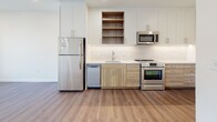 Located at 3009 W Leigh St in Richmond, Virginia, this single-floor unit offers a thoughtfully designed contemporary interior with a cohesive palette of neutral tones and modern materials throughout.

The kitchen is a standout feature, outfitted with a full suite of stainless steel appliances, including a refrigerator, electric range, over-the-range microwave, and dishwasher. Cabinetry combines crisp white upper cabinets with warm wood-toned lower cabinets and open shelving, complemented by white quartz-style countertops and a classic subway tile backsplash. Durable wood-look flooring extends through the main living areas, adding warmth to the space.

The bedroom is carpeted for comfort and features a tall, narrow window that frames views of the surrounding Richmond neighborhood, filling the room with natural light. A barn-style sliding door is also visible in the floor plan, adding a stylish architectural detail.

The bathroom is finished with large-format white tile flooring, a tub and shower combination with subway tile surround, brushed nickel fixtures, and a wood-toned vanity with an undermount sink, maintaining the modern aesthetic found throughout the unit.