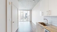 Located in the heart of Nashville, TN, this modern one-bedroom, one-bathroom unit at 505 Church Street offers a sleek, urban living experience defined by contemporary design and high-end finishes. The open-concept living and kitchen area is anchored by dramatic floor-to-ceiling windows that frame breathtaking downtown skyline views and flood the space with natural light. Exposed concrete ceilings lend an industrial character that contrasts beautifully with the crisp white walls and warm wood-look flooring that flows throughout.

The kitchen is thoughtfully appointed with granite countertops, light wood cabinetry paired with white upper cabinets, a subway tile backsplash, stainless steel appliances including a dishwasher, range, microwave, and refrigerator, and a deep undermount sink. The bedroom offers a comfortable, well-proportioned retreat with the same rich flooring and exposed concrete ceiling detail. The bathroom features large-format tile flooring, a granite-topped vanity with a backlit mirror, and a tiled walk-in shower. A dedicated entry corridor with a bold dark entry door and closet storage completes this efficiently designed, contemporary urban residence.