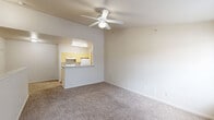 Located in Pflugerville, TX, this one-bedroom, one-bathroom residence offers a practical and comfortable layout across a well-utilized floor plan. The open living area is finished with plush carpet flooring and features a ceiling fan, creating a relaxed atmosphere. A pass-through counter connects the living space to the kitchen, which is equipped with yellow cabinetry, overhead fluorescent lighting, and essential appliances — providing a functional cooking space with a sense of openness.

A carpeted staircase with white railings leads to the upper level, where the bedroom is situated. The bedroom is a comfortably sized retreat featuring a ceiling fan, a large window that brings in natural light and outdoor views, and soft carpet underfoot. Two closets provide ample storage throughout the unit, complemented by a hallway that connects the rooms efficiently.

The full bathroom includes a tub-shower combination with classic white tile accented by a decorative tan checkerboard border, adding a touch of detail to the space. Neutral tones and clean white trim are consistent throughout, giving the home a cohesive and well-maintained appearance. The overall ambiance is practical and inviting, well-suited for comfortable everyday living.