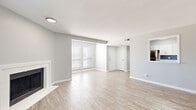 This thoughtfully designed single-floor residence offers a comfortable and functional layout encompassing one bedroom, one bathroom, a combined kitchen and living area, two hallways, and a closet. Light wood-tone flooring flows consistently throughout the entire space, creating a cohesive and airy atmosphere.

The open living room is a standout feature, highlighted by a classic white-surround fireplace and a glass-paneled exterior door that invites natural light and outdoor access. Windows fitted with blinds further brighten the space while offering privacy.

The kitchen is well-equipped and modern, featuring crisp white shaker cabinetry, white quartz countertops, a grey subway tile backsplash, and stainless steel appliances including a refrigerator, range, dishwasher, and built-in microwave. The light flooring continues here, tying the kitchen seamlessly to the living area.

The spacious primary bedroom is generously sized, offering natural light through a large window and featuring dual built-in closets with full-length mirrored doors, providing ample storage and a sense of depth.

The bathroom includes a full-size soaking tub and shower combination with white tile surround and chrome fixtures, maintaining the clean, neutral palette found throughout the home. Hallways connect each area efficiently, completing this well-organized and move-in-ready layout.