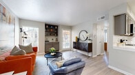 This single-story residence offers a cohesive, modern interior defined by light wood-style flooring, neutral gray walls, and white trim that flow consistently through every room. The living area is bright and open, benefiting from multiple windows with white plantation shutters that allow generous natural light. A notable built-in shelving unit with lower gray cabinetry serves as a functional accent wall, providing stylish display and storage space. The room is versatile enough to accommodate distinct seating arrangements, making it well-suited for both relaxing and entertaining.

The kitchen features gray shaker-style cabinetry with brushed nickel hardware, crisp white quartz countertops, a classic white subway tile backsplash, and stainless steel appliances including a range, microwave, and dishwasher. The layout maximizes counter and storage space efficiently.

The bedroom is a comfortable retreat, featuring a ceiling fan, a large window inviting natural light, and a roomy closet. The calm, neutral palette creates a restful atmosphere.

The bathroom continues the gray cabinetry theme with a white quartz vanity top, framed mirror, and a shower-tub combination, maintaining the clean, contemporary aesthetic found throughout the entire residence.