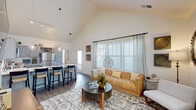 Located at 267 Grand Cypress Rd in Summerville, SC, this single-story home showcases a thoughtfully designed open-concept layout filled with natural light. The living area is a standout, boasting dramatic vaulted ceilings with clerestory windows that draw in abundant daylight. Large windows dressed with patterned curtains and wood blinds frame the space, while durable wood-style flooring runs throughout the main areas. The living room offers generous proportions, a wall-mounted flat-screen TV, and decorative accents that add warmth and character.

The kitchen is well-appointed with gray shaker-style cabinetry, stainless steel appliances including a refrigerator, range, and microwave, and a light-toned countertop that extends to a large island with bar seating for four, illuminated by pendant globe lighting. The space transitions seamlessly into the living and dining areas, making it ideal for everyday living and entertaining.

The bedrooms are comfortably sized, each featuring ceiling fans, wood-style flooring, and natural light from well-placed windows. The bathrooms are clean and functional, with gray vanity cabinetry, white countertops, and a tub-shower combination. The overall aesthetic throughout is modern yet inviting, with a cohesive neutral palette accented by warm natural tones.