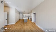 Located at 229 E Chatham St in the heart of downtown Cary, NC, this well-appointed 2-bedroom, 2-bathroom residence offers a thoughtfully designed single-level layout. The open-concept kitchen and living area serves as the centerpiece of the home, featuring white shaker cabinetry, a classic subway tile backsplash, stainless steel appliances, and a gray center island with a crisp white quartz countertop illuminated by modern glass pendant lights. The living area is bathed in natural light from a large bank of windows and includes a ceiling fan and direct access to an outdoor area. Light hardwood-style flooring flows throughout the main living spaces, enhancing the bright, airy ambiance. The primary bedroom offers comfortable proportions with plush carpeting, while its en-suite bathroom includes a white vanity with gold-toned fixtures, a tub-shower combo with tile surround, and a walk-in closet. The second bedroom is equally well-lit, with a large window and direct closet access to a shared full bathroom. Additional conveniences include in-unit laundry, a utility room, and a connecting hallway for seamless circulation. The neutral color palette and clean architectural lines give the space a fresh, modern character.