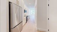 Located in Philadelphia's Mt. Airy neighborhood, this thoughtfully designed one-bedroom, one-bathroom unit offers a clean, modern aesthetic throughout. Light hardwood flooring flows seamlessly across the entire space, complementing the crisp white walls and recessed lighting that create a bright, airy atmosphere.

The galley-style kitchen is a standout feature, boasting white cabinetry with brushed gold hardware, quartz countertops, a subway tile backsplash, and a full suite of stainless steel appliances including a refrigerator, range, microwave, and dishwasher. A gold-toned faucet adds an elegant finishing touch.

The bedroom is well-proportioned, featuring a large window that invites natural light and outdoor views of surrounding greenery. Notably tall ceilings amplify the sense of space. A dedicated walk-in closet with built-in shelving provides generous storage.

The bathroom showcases upscale finishes, including a frameless glass-enclosed shower adorned with floor-to-ceiling white tile, a marble mosaic floor, a built-in niche, and polished gold fixtures — creating a spa-like retreat. The cohesive use of gold hardware across the kitchen and bathroom ties the unit together with a refined, contemporary character.