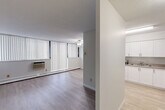Located at 935 Dundas St E in Mississauga, this 2-bedroom, 1-bathroom unit is laid out efficiently across a single floor. Light wood-style flooring runs throughout the space, creating a clean and cohesive look from room to room. The open-concept living, dining, and kitchen area forms the heart of the unit. The living room is generously proportioned, featuring a ceiling fan, a wall-mounted air conditioning unit, and large windows dressed with vertical blinds that allow for ample natural light. The kitchen is well-equipped with white shaker-style cabinetry, ample upper and lower storage, a double sink, and white appliances including a stove and refrigerator. Textured ceilings are present throughout the unit. Both bedrooms offer a quiet, neutral setting with light-toned walls and light wood flooring. The primary bedroom is a comfortable size and includes a closet, while the second bedroom also features built-in closet space. The full bathroom includes a soaking tub and shower combination with white square tile surround. A dedicated hallway and closet provide additional storage. This unit offers a functional and well-maintained layout suited for everyday living in a convenient Mississauga location.