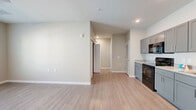 This well-designed 2-bedroom, 1-bathroom residence is laid out on a single floor, offering a practical and cohesive floor plan. Light-toned luxury vinyl plank flooring flows consistently throughout every room, complemented by neutral beige walls and crisp white trim that create a clean, modern aesthetic.

The kitchen and living room share an open-concept layout, making the space feel connected and functional. The kitchen is equipped with gray shaker-style cabinetry extending to the upper walls, granite-look countertops, and a full suite of black appliances including a refrigerator, range, microwave, and dishwasher. A double-basin sink with a window-facing orientation adds practicality to the space.

Both bedrooms are comfortably sized, with the primary bedroom offering additional square footage, a ceiling fan with light fixture, and a dedicated walk-in closet outfitted with white wire shelving systems for organized storage. The second bedroom also features a ceiling fan and a window with outdoor views, allowing for natural light.

The full bathroom is thoughtfully appointed with a dark-toned vanity featuring granite-look countertops, a walk-in shower, a separate soaking tub, and wood-look flooring that maintains design continuity. Recessed lighting and window blinds are present throughout the residence, completing a cohesive and move-in-ready interior.