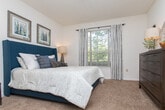 This single-floor residence offers a thoughtfully designed layout that balances comfort and functionality. The living room serves as the heart of the home, featuring rich hardwood-style flooring, elegant crown molding, and a ceiling fan overhead. Large windows allow generous natural light to fill the space, complementing the neutral walls and creating a welcoming ambiance. A bold abstract artwork anchors the sitting area, adding a vibrant focal point to the room.

The kitchen is well-equipped with ample white cabinetry, dark countertops, a decorative tile backsplash, and a peninsula with a double sink that opens toward the dining area — ideal for both everyday cooking and entertaining. The adjacent dining space connects seamlessly to the living area, enhancing the open flow of the floor plan.

The bedrooms are carpeted and tranquil, each featuring large windows dressed with patterned curtains that invite soft, natural light while maintaining privacy. The rooms offer generous space for furnishings and storage.

Both bathrooms are finished with dark countertops, white cabinetry, wood-style flooring, and large mirrors above the vanities. Each is clean and functional, with shower-tub combinations. Throughout the residence, a cohesive design palette of whites, warm neutrals, and rich wood tones creates a comfortable and inviting atmosphere.