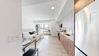 Located at 47 Bishop Richard Allen Dr in Cambridge, MA, this modern one-bedroom, one-bathroom residence offers a thoughtfully designed open-concept layout that maximizes every inch of available space. Light-toned hardwood flooring runs throughout, complementing the crisp white walls and creating a clean, cohesive aesthetic.

The kitchen is positioned along one wall and features two-tone cabinetry — warm wood-grain lower cabinets paired with light grey uppers — stainless steel appliances including a refrigerator, range, and microwave, and a single-basin undermount sink with a sleek countertop. A compact dining table nearby makes efficient use of the shared living space.

The bedroom area is generously proportioned relative to the overall footprint and benefits from large windows that invite abundant natural light and offer views of the surrounding Cambridge cityscape. The open layout allows the sleeping and living zones to coexist seamlessly.

The bathroom is well-appointed with a floating wood-tone vanity, white countertop, a large framed mirror, and a walk-in tiled shower. Clean lines and neutral finishes give it a contemporary feel.

The unit also includes a dedicated entrance and benefits from the building's modern construction, making it a practical and stylish option in the heart of Cambridge.