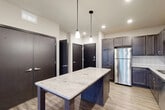 Located at 3401 E Washington Ave in Madison, WI, this well-appointed one-bedroom, one-bathroom unit offers a thoughtfully designed open-concept layout that seamlessly connects the kitchen, dining, and living areas. The kitchen is a standout feature, showcasing rich dark cabinetry, a classic white subway tile backsplash, and a striking granite-topped island with pendant lighting overhead. A full suite of stainless steel appliances — including a refrigerator, range, microwave, and dishwasher — completes the space. Wood-look flooring flows throughout the main living areas, adding warmth and continuity. The living area is bright and airy, with a ceiling fan and sliding glass doors that open onto a private balcony, inviting natural light and outdoor views. The bedroom features plush carpet, a window for natural light, and access to multiple closets, offering generous storage. Four closets throughout the unit provide exceptional organizational capacity. The bathroom is finished with dark cabinetry, a vanity with countertop, and durable wood-look flooring. Clean neutral tones, modern hardware, and consistent finishes throughout give this unit a cohesive, contemporary feel.