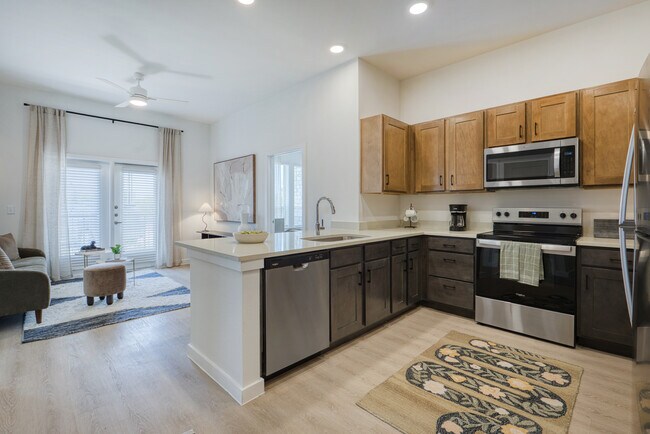 Cocina de concepto abierto con península con vista a la sala de estar en Sageland Flats en Brooks. - Sageland Flats at Brooks