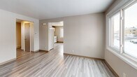 Located at 1175 George Urban Blvd in Buffalo, NY, this single-floor 2-bedroom, 1-bathroom unit offers a straightforward and efficient layout designed for comfortable everyday living. Light-toned vinyl plank flooring runs consistently throughout the space, lending a clean, cohesive look to every room.

The living room provides an open, neutral canvas with warm beige walls, a front entry door, and natural light filtering in through a window. It connects directly to the kitchen, which is well-equipped with white cabinetry, a tiled backsplash, a stainless steel sink, and white appliances including a refrigerator and electric range — offering ample storage and functionality in a compact footprint.

A central hallway connects the main living areas to the two bedrooms and bathroom. The primary bedroom is a comfortable size, featuring two windows that bring in natural light and views of the surrounding neighborhood. The second bedroom also includes a window and offers a cozy, versatile space. Both rooms continue the neutral color palette and matching flooring found throughout.

The bathroom is finished with full white tile surrounding a tub-shower combination, paired with chrome fixtures for a clean, classic look. The consistent use of light tones, updated flooring, and practical finishes throughout gives this unit a tidy, move-in-ready quality.