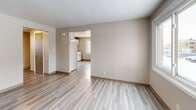 Located at 1175 George Urban Blvd in Buffalo, NY, this single-floor 2-bedroom, 1-bathroom unit offers a straightforward and efficient layout designed for comfortable everyday living. Light-toned vinyl plank flooring runs consistently throughout the space, lending a clean, cohesive look to every room.

The living room provides an open, neutral canvas with warm beige walls, a front entry door, and natural light filtering in through a window. It connects directly to the kitchen, which is well-equipped with white cabinetry, a tiled backsplash, a stainless steel sink, and white appliances including a refrigerator and electric range — offering ample storage and functionality in a compact footprint.

A central hallway connects the main living areas to the two bedrooms and bathroom. The primary bedroom is a comfortable size, featuring two windows that bring in natural light and views of the surrounding neighborhood. The second bedroom also includes a window and offers a cozy, versatile space. Both rooms continue the neutral color palette and matching flooring found throughout.

The bathroom is finished with full white tile surrounding a tub-shower combination, paired with chrome fixtures for a clean, classic look. The consistent use of light tones, updated flooring, and practical finishes throughout gives this unit a tidy, move-in-ready quality.