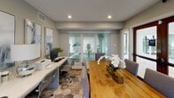 Located at 4010 Linkwood Dr in Houston, Texas, this single-floor business center offers a well-appointed, modern workspace designed to support both focused productivity and collaborative work. The space is finished with neutral gray walls and recessed lighting that creates a bright, professional atmosphere throughout.

A central conference table crafted from warm natural wood provides ample seating for meetings or group work, complemented by upholstered gray chairs. Adjacent to the table, a dedicated workstation area features a long white quartz-topped desk equipped with multiple computer terminals, a printer, and ergonomic office chairs — accommodating several users simultaneously.

Distinctive hexagonal floor tiles add visual interest underfoot, transitioning seamlessly across the workspace. Large windows dressed with white horizontal blinds allow generous natural light to fill the room while maintaining privacy. A glass-paneled wall and door offer a view into an adjacent fitness facility, enhancing the sense of openness and connectivity between amenity spaces.

Decorative framed abstract artwork in cool blue and gray tones adorns the walls, lending a polished, contemporary aesthetic. Thoughtful touches such as potted greenery and floral arrangements contribute a welcoming ambiance. A glass-paneled entry door provides easy access to the exterior, rounding out this functional and stylish shared amenity space.