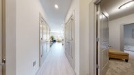 This well-designed single-floor unit offers a thoughtful layout that balances open communal spaces with comfortable private areas. A wide, light-filled hallway with light wood-style flooring, white walls, and paneled gray doors with gold hardware provides an elegant transition between rooms, leading toward the main living area.

The kitchen is a standout feature, showcasing crisp white shaker cabinetry, granite countertops, a classic subway tile backsplash, and a full suite of stainless steel appliances including a range, over-the-range microwave, and refrigerator. A central island with pendant lighting and bar seating makes it ideal for both meal preparation and casual dining.

The living room is bright and airy, benefiting from large windows that invite abundant natural light and offer views of the surrounding urban landscape. The open layout comfortably accommodates a seating area and flows naturally from the kitchen.

The bedrooms are carpeted for comfort, with the primary bedroom featuring a large window with outdoor views and direct access to the living space. A bathroom with light wood-style flooring includes a walk-in shower with a curtain enclosure, finished in clean, neutral tones.

Throughout the unit, the consistent use of light flooring, white walls, and modern fixtures creates a cohesive, contemporary ambiance.