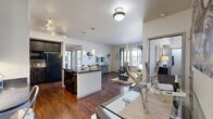 Located in Broomfield, Colorado, this well-designed two-bedroom, two-bathroom residence offers a comfortable and stylish single-level layout. The open-concept living and dining area is anchored by rich hardwood flooring and large windows that fill the space with natural light, with a sliding glass door providing outdoor access from the living room. The kitchen is a standout feature, boasting dark cabinetry, granite countertops with a tile backsplash, a breakfast bar with pendant lighting, and track lighting overhead — ideal for both cooking and casual dining. A connecting hallway lined with hardwood floors leads to the private quarters. The primary bedroom features vaulted ceiling details, a ceiling fan, plush carpet, a walk-in closet, and windows with outdoor views. Its en-suite bathroom includes dark vanity cabinetry with granite countertops and a framed mirror. The second bedroom offers a cozy, well-proportioned retreat with soft carpet. The second bathroom features a soaking tub, granite-topped vanity, and clean tile flooring. Each bedroom includes its own closet. The residence is completed by a central hallway with additional storage, making this a highly functional and thoughtfully laid-out home.