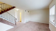This two-story home in College Park, Georgia offers a practical and straightforward layout spread across two levels. The main level centers around a generously sized living area finished with plush carpet flooring and neutral cream-toned walls, creating a clean, understated backdrop. A staircase with a black metal railing connects the floors, adding a subtle structural detail to the space. The kitchen is equipped with white cabinetry offering ample storage, granite-patterned countertops, a double sink, and black appliances including an electric range, dishwasher, and a full-size refrigerator. Wood-look flooring runs throughout the kitchen, adding warmth and easy maintenance. A half bathroom on the main level features wood-look flooring, a compact white vanity with a mirror, and a towel bar. Upstairs, the primary bedroom is a spacious retreat with soft carpet, multiple windows that invite natural light and outdoor views, and access to a walk-in closet. An additional room on the upper level features wood-look plank flooring and clean walls. The full upstairs bathroom includes a shower-tub combination, white vanity, and a large mirror with overhead lighting.
