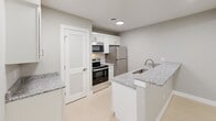 Located at 4949 Garfield Rd in Auburn, MI, this thoughtfully designed 2-bedroom, 1-bathroom single-floor unit offers a functional and modern living experience. The open-concept layout seamlessly connects the kitchen, dining, and living areas, creating a bright and cohesive shared space. Light-toned luxury vinyl flooring flows throughout the main living areas, complemented by neutral gray walls and clean white trim.

The kitchen is well-appointed with white shaker-style cabinetry, granite countertops, stainless steel appliances including a range, microwave, and refrigerator, and a peninsula with an undermount sink — ideal for both cooking and casual dining. A pantry with a louvered door adds generous storage.

Both bedrooms feature plush carpeting, dedicated closets, and a calm, neutral palette. The primary bedroom includes sliding glass door access to a private balcony overlooking the neighborhood. The second bedroom benefits from a large window that fills the room with natural light.

The full bathroom is clean and efficient, featuring a white vanity with ample counter space, a mirrored medicine cabinet, and a full tub/shower combination. Additional conveniences include a dedicated laundry area and multiple closets throughout, maximizing storage in this efficiently designed home.