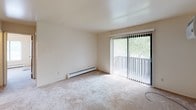 Located at 3233–3249 Shaffer Ave SE in Kentwood, Michigan, this single-floor unit offers a straightforward, functional layout designed for comfortable everyday living. The living area is carpeted and filled with natural light, courtesy of a full sliding glass door fitted with vertical blinds that opens to an outdoor balcony. A wall-mounted air conditioning unit and baseboard heating ensure year-round climate control throughout the space. The galley-style kitchen is efficiently organized, featuring white cabinetry with wood-accented hardware, a double stainless steel sink, a gas range, and a full-size refrigerator, all set atop durable tile flooring. Two carpeted bedrooms each benefit from natural light provided by windows fitted with horizontal blinds, along with baseboard heating for individual comfort. The full bathroom includes a single vanity with a mirror cabinet, a toilet, and a tub-shower combination with white tile surround. Throughout the unit, neutral tones on the walls and ceilings create a clean, cohesive aesthetic. The layout, as revealed by the overhead dollhouse view, is compact yet well-organized, with clearly defined spaces that flow logically from one area to the next.