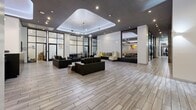 Located on Wilshire Boulevard in the heart of Los Angeles, this expansive commercial space offers a sophisticated and modern environment across a single floor. The grand lobby serves as the centerpiece, featuring a striking tray ceiling with integrated LED lighting that casts a warm, ambient glow over the open floor plan. Light wood-look tile flooring extends throughout, creating a clean, cohesive aesthetic that complements the contemporary design.

Floor-to-ceiling black-framed glass partitions divide interior sections while maintaining visual openness and allowing natural light to filter through. Skylights further enhance the brightness of the space. The lobby is furnished with sleek black leather seating arrangements and modern accent tables, creating comfortable and professional reception areas. Elevator banks are conveniently positioned within the main hall, alongside additional utility rooms including a dedicated fire control room.

The hallways feature exposed concrete accent walls juxtaposed against white painted surfaces, adding an industrial-chic character. A sputnik-style chandelier provides a refined design focal point in one corridor. The property also includes a structured parking garage with clearly marked spaces, accessible restroom facilities, and multiple utility access points, making this a fully functional and well-appointed commercial destination.