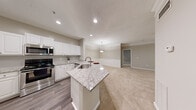 This single-floor residence offers a thoughtfully designed open-concept layout that seamlessly connects the kitchen and living areas. The kitchen serves as the heart of the home, showcasing granite countertops, a central island with a built-in sink, crisp white cabinetry, a subway tile backsplash, and a full suite of stainless steel appliances including a range, microwave, dishwasher, and refrigerator. Recessed lighting and hardwood-style flooring complete the kitchen's polished look.

The living room is generously sized, featuring plush carpeting, crown molding, a ceiling fan, and a glass-paneled door that invites natural light and provides outdoor access. The neutral warm-gray wall tones create a calm, cohesive ambiance throughout the home.

The bedrooms are carpeted and well-proportioned, each offering ceiling fans and natural light from window treatments with blinds. Several bedrooms include closets with six-panel doors, offering practical storage. One bedroom features an ensuite bathroom, providing added privacy.

The bathroom is cleanly finished with a granite-topped white vanity, a framed mirror, wood-look tile flooring, and contemporary lighting fixtures. Every detail of this residence reflects a consistent, modern aesthetic that balances comfort and functionality.