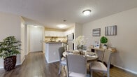 This single-story residence offers a thoughtfully designed layout that balances functionality and comfort throughout its interconnected living spaces. The kitchen serves as a central hub, featuring white cabinetry with raised-panel doors, stainless steel appliances including a range, refrigerator, and dishwasher, and a peninsula with a neutral-toned countertop that provides additional workspace and casual seating. Wood-look flooring runs through the kitchen and dining area, adding warmth and visual continuity.

The adjacent dining area accommodates a full-sized table and flows naturally toward the living room, which is anchored by a tile-surround fireplace and a sliding glass door that brings in natural light and outdoor views. The living room's wood-look flooring continues the cohesive aesthetic established throughout the common areas.

The bedrooms are carpeted and finished with ceiling fans, offering a quieter, softer atmosphere. The primary bedroom includes an en-suite bathroom equipped with a tub-shower combination, white vanity cabinetry, a granite-toned countertop, and a large mirror with overhead lighting.

A dedicated laundry area accommodates full-sized, top-loading washer and dryer units with overhead shelving for storage. Textured ceilings are consistent throughout, and the overall palette of neutral tones creates a calm and welcoming ambiance.