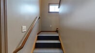 Located at 1410 Deer Lakes Dr in Buffalo, NY, this two-story, one-bedroom, one-bathroom home offers a practical and comfortable layout across two levels. The entry level features a carpeted living area bathed in natural light through a large window with wood-trimmed blinds, alongside a front door with a sidelight panel. A staircase connects the entry to the upper level, where the majority of the living space is found.

The galley-style kitchen is a standout feature, offering ample warm-toned wood cabinetry, a full suite of black appliances including a refrigerator, range, dishwasher, and microwave, as well as a double sink with light countertops. A skylight and window provide natural light, and a stacked washer and dryer unit adds convenient in-unit laundry.

The spacious primary bedroom features plush carpeting, a ceiling fan with light fixture, and a generously sized window overlooking the outdoors, filling the room with natural light. A closet provides dedicated storage. The full bathroom is well-appointed with warm wood cabinetry, a dark countertop vanity, a large mirror, a tub/shower combo, and durable tile flooring. Throughout the home, warm neutral wall tones, wood-trimmed doors, and consistent finishes create a cohesive and inviting atmosphere.