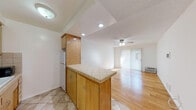 Located at 1776 N Sycamore Ave in the heart of Hollywood, Los Angeles, this single-floor residence offers a functional and comfortable layout with a clean, neutral aesthetic throughout. The kitchen is equipped with warm oak cabinetry, a tile backsplash, a gas range, and ample upper and lower cabinet storage. A peninsula with a tiled countertop extends into the living area, creating an open, connected flow ideal for casual dining or meal prep. Tile flooring grounds the kitchen, transitioning seamlessly to light-toned hardwood floors that extend through the living and bedroom areas. The living room is bright and airy, featuring a ceiling fan with light fixture, a large sliding glass door dressed with vertical blinds, and a wall-unit air conditioner — allowing for generous natural light and comfortable temperature control. The bedroom is a calm, well-lit space with hardwood floors, vertical blinds, and a textured ceiling. The bathroom includes a combined shower and soaking tub with sliding glass doors, beige tile surround, and a vanity with chrome hardware. Recessed lighting and flush-mount fixtures provide consistent illumination throughout the space.