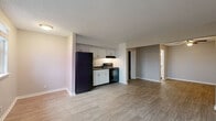 Located at 320 Plus Park Blvd in Nashville, TN, this single-floor unit offers a functional and efficient layout designed to maximize every square foot. The open-concept living and kitchen area forms the heart of the space, creating a seamless flow between cooking and relaxing zones. The kitchen is equipped with white cabinetry, dark granite-style countertops, a black refrigerator, a black electric range with an overhead ventilation hood, and a sink — providing all essential appliances in a well-organized workspace. Natural light filters into the living area through a window, complementing the warm, neutral-toned walls and light wood-look flooring that runs consistently throughout the unit. A wall-mounted HVAC unit in the living area ensures year-round climate control. The bathroom is clean and efficiently designed, featuring a full bathtub with a curved shower rod, a toilet, and light tile flooring, all finished in crisp white tones for a fresh, tidy appearance. Textured ceilings and clean white baseboards add a classic touch to the overall aesthetic. The unit's straightforward, practical design makes it a well-suited space for those seeking comfortable, low-maintenance living in Nashville.