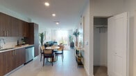 This single-floor residence in Miami, FL offers a thoughtfully designed open-concept layout where the living, dining, and kitchen areas flow seamlessly together. Large floor-to-ceiling windows and a private balcony at the end of the living space flood the interior with natural light while framing expansive city views, creating an airy, welcoming atmosphere throughout.

The kitchen is well-appointed with rich walnut-toned cabinetry accented by gold hardware, a white tile backsplash, light stone countertops, and a full suite of stainless steel appliances including a French door refrigerator, range, microwave, and dishwasher. Adjacent to the kitchen, the dining area comfortably accommodates a round marble-top table, enhancing the space's modern aesthetic.

The living room features a ceiling fan, ample natural light, and direct balcony access through a full-height sliding glass door. A dedicated closet near the entry provides convenient storage.

The bedroom offers natural light through a large window with outdoor views, a ceiling fan, and an open closet with built-in shelving. The bathroom includes a tub-shower combination with marble-style surround tile, a walnut vanity with gold fixtures, and neutral tile flooring, completing this contemporary Miami residence.
