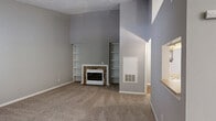 Located at 3800 Meriwether Dr in Durham, NC, this single-floor, one-bedroom, one-bathroom residence offers a well-organized layout across a comfortable footprint. The living room serves as the heart of the home, featuring plush carpeting, vaulted ceilings, a textured ceiling finish, and a stone-accented fireplace flanked by built-in shelving — ideal for both relaxing and entertaining. A large window invites abundant natural light, while a pass-through opening connects the living area to the kitchen. The kitchen is appointed with dark walnut cabinetry, light quartz-style countertops, and black appliances including a range and over-the-range microwave, offering both functionality and style. The spacious bedroom continues the vaulted ceiling design and features soft carpeting and a sliding glass door that opens directly onto a private balcony with green, tree-lined views. The bathroom includes a full tub-shower combination with clean white surrounds. A dedicated laundry room provides added convenience, complete with a full-size washer and dryer, rich hardwood-style flooring, and dark upper cabinetry for storage. A hallway and closet round out this thoughtfully designed residence.