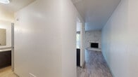 Located at 1251 S Bellaire St in Denver, CO, this studio offers a well-organized single-floor layout comprising a living area, a pass-through kitchen, and a full bathroom. The living area is a standout space, anchored by a white-painted stacked stone accent wall that frames a classic fireplace with a raised tile hearth. Sliding glass doors open directly onto a private balcony, flooding the interior with natural light and providing pleasant views of mature surrounding trees. Light wood-tone vinyl plank flooring runs throughout, lending warmth and visual continuity to the space. The kitchen is efficiently arranged and accessible via a pass-through counter with a granite-style surface, complemented by white cabinetry and under-cabinet lighting. The full bathroom features a white tiled tub-shower combination with a curved curtain rod, maintaining a clean and functional aesthetic. The private balcony offers a quiet outdoor retreat surrounded by lush tree canopy. Overall, the studio presents a bright, open ambiance with notable architectural character, combining practical design elements with distinct mid-century-inspired details throughout.