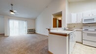 Located on West Main Street in Sun Prairie, Wisconsin, this single-floor unit showcases a thoughtfully designed open-concept layout highlighted by striking vaulted ceilings that lend an impressive sense of height and airiness throughout the main living area. The living room is generously proportioned, finished with wall-to-wall carpeting, and benefits from abundant natural light provided by a sliding glass door fitted with vertical blinds, which opens to an outdoor area. A ceiling fan adds comfort, and a wall-mounted HVAC unit ensures year-round climate control.

The kitchen is well-equipped with white cabinetry extending to the vaulted ceiling, a full suite of white appliances including a refrigerator, electric range, microwave, and dishwasher, and tile-style flooring. A peninsula with a built-in sink and breakfast bar connects the kitchen to the living area, creating a seamless flow.

The bedroom features plush carpeting, a large window with blinds, and a baseboard heating unit. Ample closet storage is also present. Two bathrooms serve the unit—one with a tub/shower combination and vanity, and one with a vanity and large mirror. A dedicated in-unit laundry area accommodates a full-size washer and dryer, adding everyday convenience.