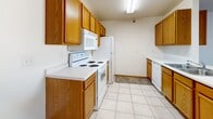 Located at 1301 Belsly Blvd in Moorhead, MN, this one-bedroom, one-bathroom unit offers a practical and comfortable single-floor layout. The galley-style kitchen is well-appointed with warm oak cabinetry providing generous storage, white appliances including a range, over-the-range microwave, refrigerator, and dishwasher, and light tile flooring. A peninsula with a double sink and additional counter space creates an open connection between the kitchen and living area in select configurations. The living room is carpeted and features a ceiling fan, a baseboard heating unit, and a sliding glass door with vertical blinds that fills the space with natural light and provides outdoor access. The bedroom is a comfortable size, featuring plush carpet, a window with natural light, and baseboard heating. A dedicated closet provides ample storage. The bathroom includes a vanity with oak cabinetry, tile flooring, and a clean, functional layout. Textured ceilings are present throughout, adding a classic residential character. The overall design is straightforward and efficient, offering a well-organized living environment suited for comfortable everyday living.