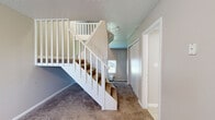 Located at 350 Manchester Ct in Decatur, Illinois, this two-story residence offers a functional and straightforward layout spread across two levels. The main floor features tile flooring in utility areas and transitions to soft, neutral-toned carpet throughout the living spaces. A white-railed staircase with carpeted treads connects the two floors, lending a clean, classic look to the interior.

The bathroom is well-appointed with a full tub and shower combo, white tile surround, light ceramic tile flooring, and a warm wood-toned vanity with a white countertop and mirrored medicine cabinet above.

The upper level showcases vaulted and angled ceilings that add visual height and character to the bedrooms. Each carpeted bedroom benefits from natural light through standard windows, with one room featuring a wall-mounted HVAC unit for individual climate control and another equipped with baseboard heating. Closet space is provided in the upper-level rooms, including a sliding-door closet in one bedroom.

Throughout the home, textured ceilings, neutral wall tones, and clean white trim create a cohesive, understated aesthetic. The layout is practical and well-suited for comfortable everyday living.