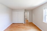Located at 114 Horizon Dr in Edison, NJ, this single-floor residence offers a well-organized layout with warm, polished hardwood flooring extending throughout the main living areas and bedrooms. The open living and dining area is bright and generously proportioned, featuring an elegant chandelier, a sliding glass door that opens to a green outdoor view, and a wall-unit air conditioner accompanied by baseboard heating. Natural light flows in through window treatments, enhancing the clean, neutral color palette of the white walls.

The kitchen is efficiently designed in a galley layout, featuring warm-toned wood cabinetry, dark granite-style countertops, a tiled backsplash, and white appliances including a gas range, dishwasher, and refrigerator. Light-speckled vinyl flooring grounds the space practically.

The two bedrooms are comfortably sized, each featuring gleaming hardwood floors, white walls, and built-in closets with bifold doors. Baseboard heating provides year-round comfort in these rooms.

The bathroom is finished with neutral beige tile on the floors and walls, and includes a single-sink vanity with wood cabinetry, a toilet, and a full tub-shower combination. The overall ambiance of the residence is clean, functional, and move-in ready.