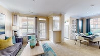 This single-floor residence is thoughtfully designed with warm, neutral tones and crown molding that run throughout, creating a cohesive and polished aesthetic. The living room serves as a central gathering space, featuring a tile-surround fireplace, plush carpeting, and a glass-paneled entry door that fills the room with natural light. An arched alcove near the foyer adds architectural character, while a pass-through opening connects the living area to the kitchen.

The kitchen is outfitted with white cabinetry, white countertops, a ceramic tile floor, and a full suite of appliances including an electric range with an over-the-range microwave. The adjacent dining area accommodates a full-sized table and benefits from large windows with outdoor views.

Two well-sized bedrooms each feature carpeted floors, ceiling fans or ample overhead lighting, and generous windows. The bathroom presents a wide vanity with a large mirror, tile flooring, and built-in storage. A dedicated laundry area houses a full-sized washer and dryer. Throughout the residence, consistent warm wall tones and natural light contribute to a comfortable, inviting atmosphere.