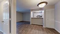 This single-floor residence offers a thoughtfully designed layout that balances open communal spaces with private retreats. The living and dining areas flow seamlessly together, both finished with rich, dark hardwood-style flooring that adds warmth and continuity throughout. A pendant light fixture anchors the dining space, while a ceiling fan in the adjoining area enhances comfort. The kitchen is positioned behind a pass-through counter with a raised bar, featuring crisp white cabinetry with brushed nickel hardware, a mosaic tile backsplash, light stone-look countertops, and black appliances including a coil-top range with an overhead vent hood. Recessed track lighting illuminates the kitchen efficiently. The bedrooms are carpeted in neutral tones and receive ample natural light through large windows with exterior views. Each room offers closet access via classic six-panel doors. The bathrooms are finished with hardwood-style flooring, white vanities, and full tub-shower combinations equipped with chrome fixtures and grab bars. Clean, neutral wall tones are carried throughout the entire residence, contributing to a cohesive and move-in-ready aesthetic that is both functional and inviting.
