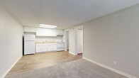 Located at 965 Candle Light Blvd in Brooksville, Florida, this single-story unit offers a practical and well-organized layout designed for comfortable everyday living. The interior is finished with a neutral gray and white color palette throughout, creating a clean and cohesive aesthetic.

The kitchen is efficiently designed with crisp white cabinetry, light granite-look countertops, and white appliances including a refrigerator and electric range. A flush skylight panel overhead provides bright, even illumination, and the space flows directly into the adjacent living area. Wood-look vinyl plank flooring runs through the kitchen and main living zones, offering durability and easy maintenance.

The living area is open and well-proportioned, with a front entry door flanked by a window that brings in natural light. Soft carpet transitions from the entry into the living space, adding warmth underfoot.

The bedrooms are carpeted and quietly neutral, each featuring windows with blinds. One bedroom includes a ceiling fan with light fixture and a built-in closet with wire shelving, providing organized storage. The textured ceilings are consistent throughout the unit.

The bathroom is clean and functional, featuring a white vanity with solid countertop, a tub/shower combination, and wood-look flooring that ties back to the rest of the unit's design. Overall, the space presents a move-in ready environment with consistent finishes and a straightforward, livable layout.