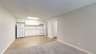 Located at 965 Candle Light Blvd in Brooksville, Florida, this single-story unit offers a practical and well-organized layout designed for comfortable everyday living. The interior is finished with a neutral gray and white color palette throughout, creating a clean and cohesive aesthetic.

The kitchen is efficiently designed with crisp white cabinetry, light granite-look countertops, and white appliances including a refrigerator and electric range. A flush skylight panel overhead provides bright, even illumination, and the space flows directly into the adjacent living area. Wood-look vinyl plank flooring runs through the kitchen and main living zones, offering durability and easy maintenance.

The living area is open and well-proportioned, with a front entry door flanked by a window that brings in natural light. Soft carpet transitions from the entry into the living space, adding warmth underfoot.

The bedrooms are carpeted and quietly neutral, each featuring windows with blinds. One bedroom includes a ceiling fan with light fixture and a built-in closet with wire shelving, providing organized storage. The textured ceilings are consistent throughout the unit.

The bathroom is clean and functional, featuring a white vanity with solid countertop, a tub/shower combination, and wood-look flooring that ties back to the rest of the unit's design. Overall, the space presents a move-in ready environment with consistent finishes and a straightforward, livable layout.