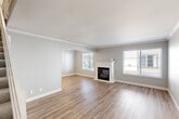 This two-story residence in South San Francisco offers a thoughtfully laid-out floor plan across two levels. The main floor features an open-concept living room and kitchen area. The living room is a bright, welcoming space adorned with crown molding, light wood-style flooring, and multiple windows that flood the room with natural light. A white-mantled fireplace serves as a focal point, adding warmth and character to the space. The kitchen is well-appointed with white shaker cabinets, quartz-style countertops, a gray subway tile backsplash, stainless steel appliances, and a double sink — combining both style and functionality. Upstairs, two carpeted bedrooms provide comfortable retreats, each with natural light from windows with blinds. The primary bedroom includes a closet and ceiling fan, while the second bedroom also features a built-in closet. The shared full bathroom is finished with modern wood-toned cabinetry, a quartz vanity, and a tiled shower-tub combination. A staircase connects the two levels through a hallway. The neutral color palette and clean finishes throughout create a cohesive, move-in ready aesthetic.