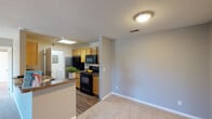 This single-story residence is designed with a practical and functional layout that maximizes the use of its living spaces. The open-concept living area features neutral-toned carpet and flows directly into the kitchen via a peninsula counter with a granite-style surface, providing both a visual divide and a convenient breakfast bar. The kitchen is laid out in a galley style, equipped with black appliances including a refrigerator, electric range, microwave, and dishwasher. Light wood cabinetry lines both walls, offering ample storage, while a skylight overhead brings natural brightness into the space. Wood-look flooring runs throughout the kitchen.

The unit includes two carpeted bedrooms, each featuring windows that allow natural light and outdoor views of surrounding greenery. One bedroom includes a private en-suite bathroom, while a second full bathroom serves the remainder of the unit. Both bathrooms are finished with granite-style countertops, warm wood vanity cabinets, and wood-look flooring. The primary bathroom includes a tub-shower combination. Neutral gray walls and consistent finishes throughout give the space a cohesive and understated aesthetic.