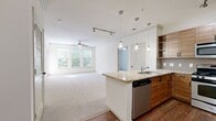 This well-appointed 970-square-foot, single-floor apartment offers 3 bedrooms, 2 bathrooms, and 2 closets across a thoughtfully designed layout. The open-concept kitchen and living area serves as the heart of the home, featuring rich wood cabinetry, granite countertops, stainless steel appliances including a gas range and refrigerator, hardwood flooring, track lighting, and elegant pendant lights over the kitchen island. The living room is bright and spacious, with large windows, crown molding, and a ceiling fan that invite abundant natural light and outdoor views. A glass door leads to a private balcony overlooking a lush, tree-lined courtyard. The primary bedroom measures 210 square feet and is complemented by a walk-in closet with built-in wire shelving and an en-suite bathroom featuring tile flooring, a vanity with a granite countertop, and a tub-shower combination. The secondary bedrooms are carpeted, each equipped with ceiling fans and windows that frame greenery views. The second bathroom mirrors the first with clean tile floors, a white vanity, and a full tub-shower. Throughout, the unit maintains a neutral, light color palette with plush carpeting in living and bedroom areas, creating a calm and functional living environment.