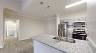 This single-floor, 2-bedroom, 1-bathroom residence in Cordova, Tennessee offers a thoughtfully designed layout with modern finishes throughout. The kitchen is a standout feature, equipped with grey shaker-style cabinetry, granite countertops, a hexagonal tile backsplash, stainless steel appliances, and a peninsula with an undermount sink — all accented by crown molding and wood-look flooring. The living room is bright and inviting, highlighted by a classic fireplace with a white mantel, a ceiling fan, and French doors that open to a private balcony, allowing ample natural light to fill the space. Both bedrooms are carpeted for comfort and include ceiling fans and windows that bring in natural light. The primary bedroom features a walk-in closet, while the second bedroom includes a standard closet. The bathroom is equipped with a large soaking tub surrounded by white tile, a grey vanity with a dark countertop, and a window for natural ventilation. Hallways connect the rooms efficiently, and the overall palette of neutral tones and clean finishes gives the entire residence a bright, contemporary feel.
