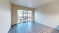 Located in Kirkland, WA, this well-appointed one-bedroom, one-bathroom unit offers a thoughtfully designed single-floor layout. The open-concept kitchen and living area serves as the heart of the home, featuring striking granite countertops on a central island with bar seating, dark espresso cabinetry, stainless steel appliances including a refrigerator, range, and microwave, and stylish pendant and track lighting. Hardwood-style flooring flows throughout the main living areas, lending a clean, modern aesthetic. The living area is bright and airy, highlighted by large sliding glass doors that open to a private balcony with views of the surrounding Kirkland neighborhood and lush Pacific Northwest greenery. The bedroom is comfortably sized with plush carpeting, a window offering natural light and outdoor views, and access to a dedicated walk-in closet with wire shelving. Additional storage is provided by multiple closets throughout the unit. The bathroom is finished with granite countertops, dark cabinetry, a combined tub/shower, and hardwood-style flooring. A hallway entrance and in-unit laundry add everyday convenience. Neutral warm tones and clean lines throughout create a calm, inviting atmosphere.