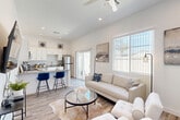 Located at 5821 W McDowell Rd in Phoenix, AZ, this efficiently designed single-story, one-bedroom, two-bathroom home delivers a clean, modern aesthetic throughout. The open-concept living and kitchen area serves as the heart of the home, bathed in natural light from large windows and a sliding glass door that leads to a private, fenced outdoor patio — perfect for enjoying the Arizona sunshine. Elevated ceilings and a ceiling fan enhance the airy feel of the living space, which features wood-look plank flooring that flows seamlessly throughout.

The kitchen is outfitted with white shaker cabinetry, gray quartz-style countertops, a tiled backsplash, and a full suite of stainless steel appliances including a range, microwave, refrigerator, and dishwasher. A peninsula with seating provides a casual dining option and connects the kitchen to the living area.

A hallway leads to the well-proportioned bedroom, which features a double-door closet, a window with outdoor views, and vaulted ceilings that add to the sense of space. Two bathrooms, both finished with white cabinetry and wood-look flooring, offer functional convenience. The overall palette of crisp whites and neutral tones creates a bright, welcoming ambiance throughout the home.