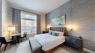 Located at 250 McHenry Rd in Buffalo Grove, IL, this well-appointed one-bedroom, one-bathroom residence offers a smart and efficient layout designed for comfortable living. The generously sized bedroom serves as the heart of the home, featuring light wood-style flooring, soaring ceilings, and a striking textured accent wall that adds depth and sophistication. A large window floods the room with natural light and provides outdoor views, while a dedicated kitchenette area with cabinetry and appliances adds everyday convenience. Three closets provide ample storage throughout the space. The bathroom is finished in a clean, contemporary style, featuring a floating gray vanity with a white countertop, a framed mirror with vanity lighting, and a glass-enclosed shower, all set on light tile flooring for a bright, polished look. A dedicated laundry area houses a full-size front-loading washer and dryer, adding notable practicality to the unit. A utility room and hallway round out the layout, ensuring all functional needs are met. Throughout the residence, neutral tones, modern fixtures, and quality finishes create a cohesive and inviting ambiance suited for everyday living.